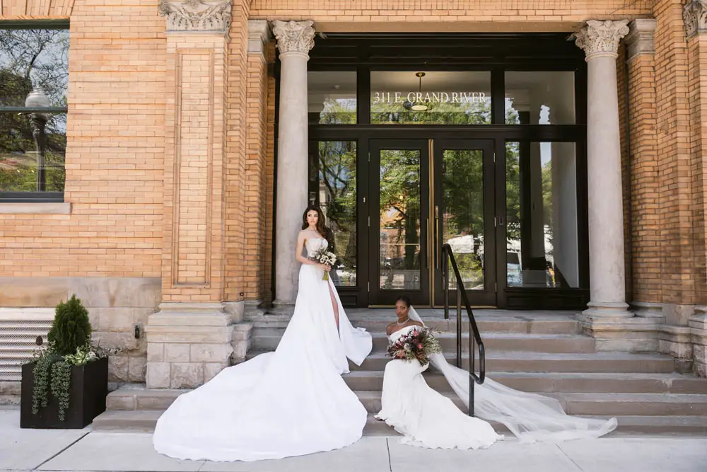two women in bride dresses sitting on stairs