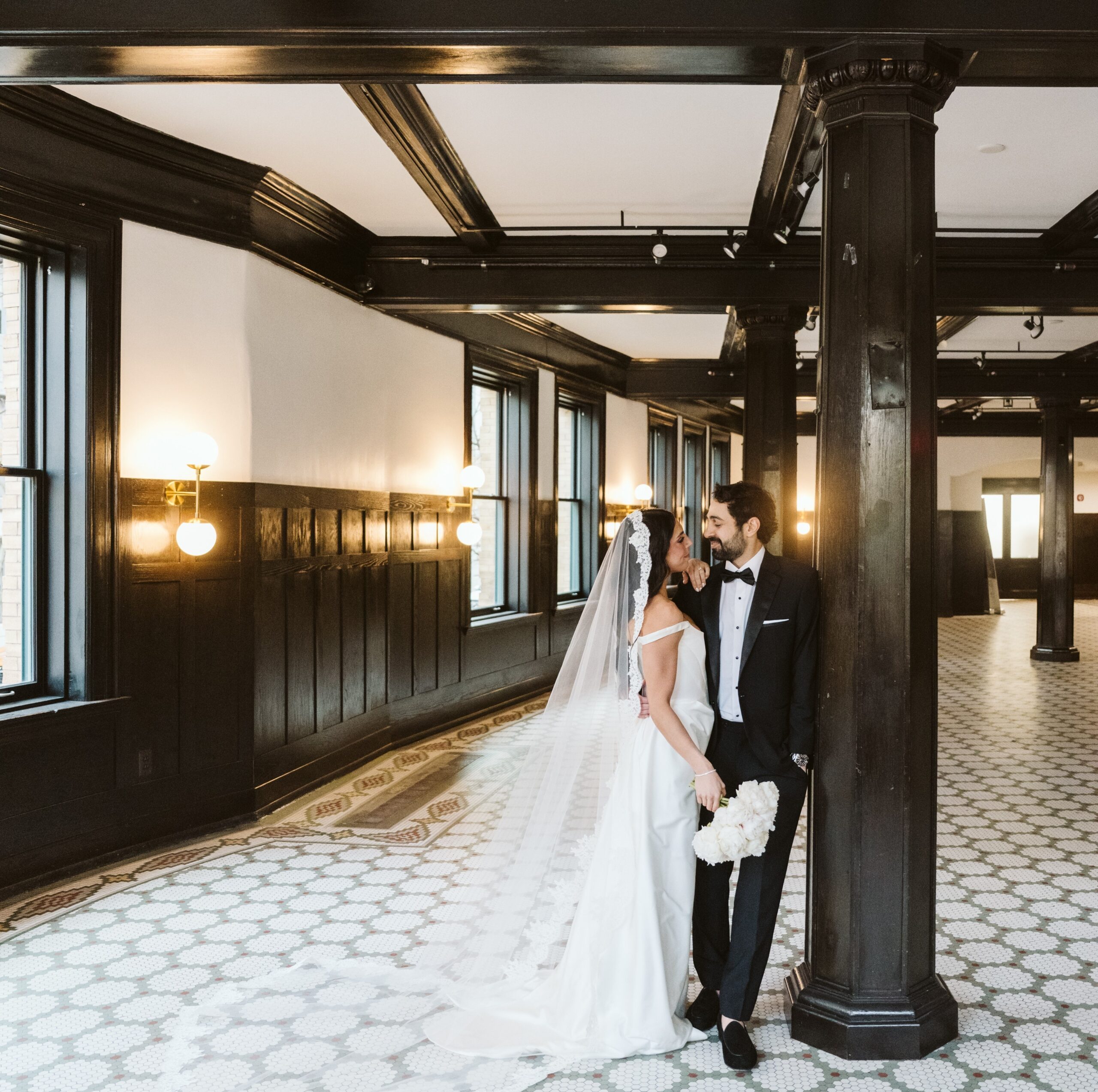 groom and bride pose in front of window